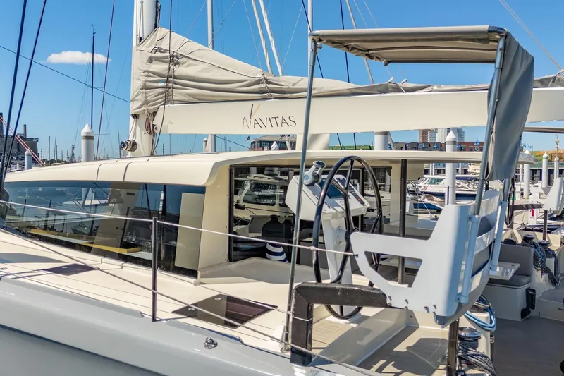 Slide: The Image of 2019 Itacatamarans 14.99 docked in a marina with cityscape background. - 14