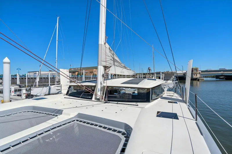 Slide: The Image of 2019 Itacatamarans 14.99 catamaran docked, showcasing deck and solar panels under clear blue sky. - 146