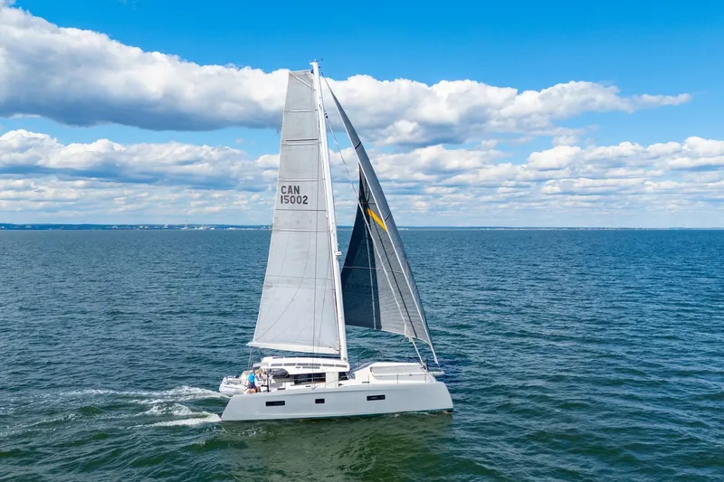 Slide: The Image of 2019 Itacatamarans 14.99 sailing catamaran with solar panels and dinghy on open water. - 2
