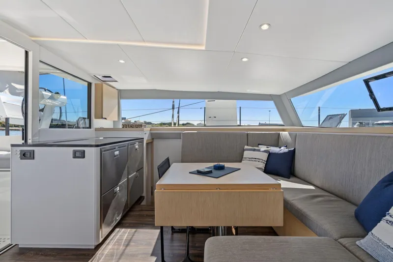 Slide: The Image of Interior of 2019 Itacatamarans 14.99, featuring seating and windows with marina view. - 48