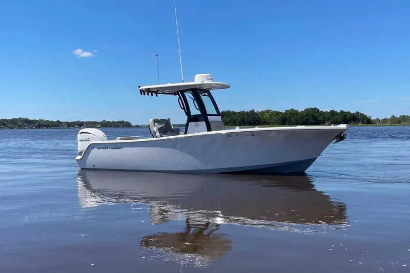 Slide: The Image of 2024 Sportsman Open 232 Center Console boat on calm water under clear blue sky. - 0