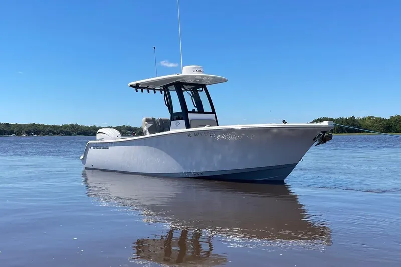 Slide: The Image of 2024 Sportsman Open 232 Center Console boat on calm water under clear blue sky. - 1