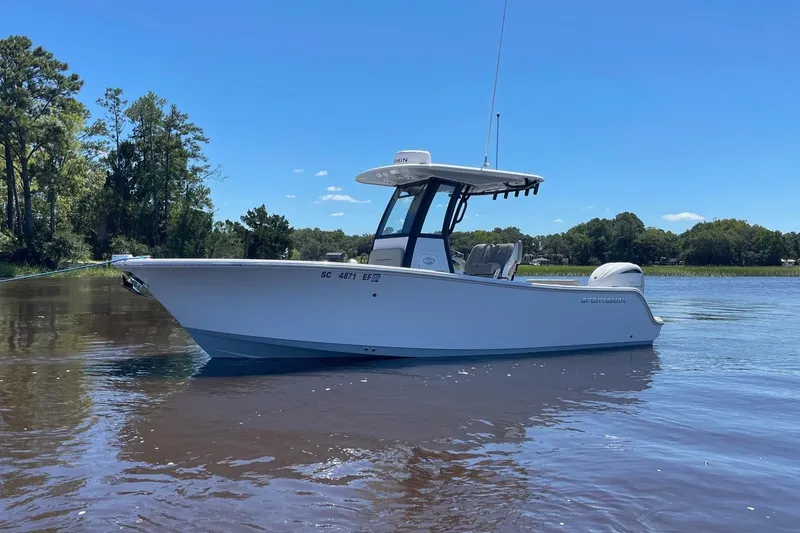 Slide: The Image of 2024 Sportsman Open 232 Center Console boat on calm water, surrounded by trees. - 2