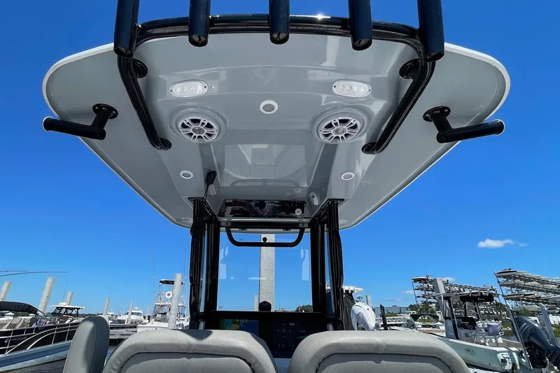 Slide: The Image of 2024 Sportsman Open 232 Center Console boat with T-top and speakers, docked under clear blue sky. - 21