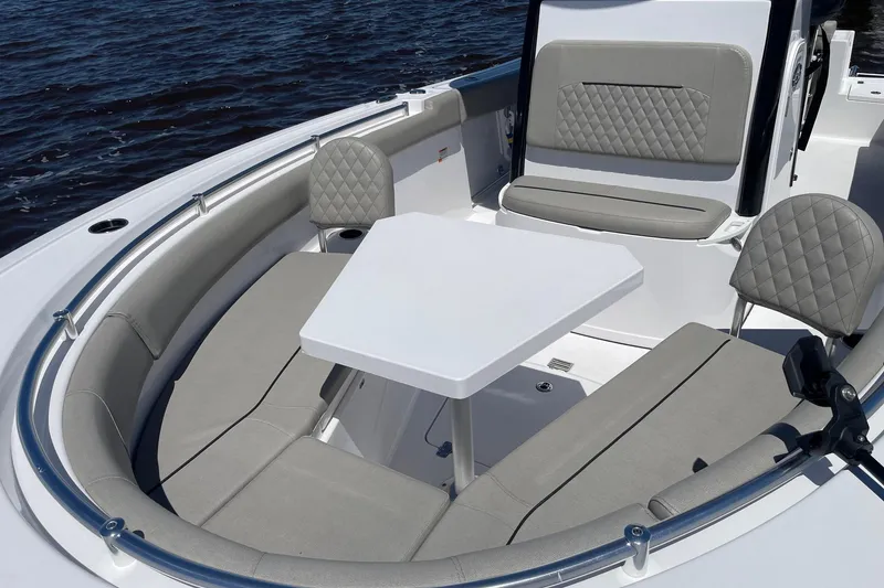 Slide: The Image of 2024 Sportsman Open 232 Center Console boat interior with seating and table on water. - 24