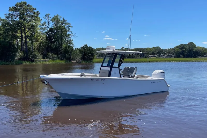 Slide: The Image of 2024 Sportsman Open 232 Center Console boat on calm water, surrounded by trees. - 3