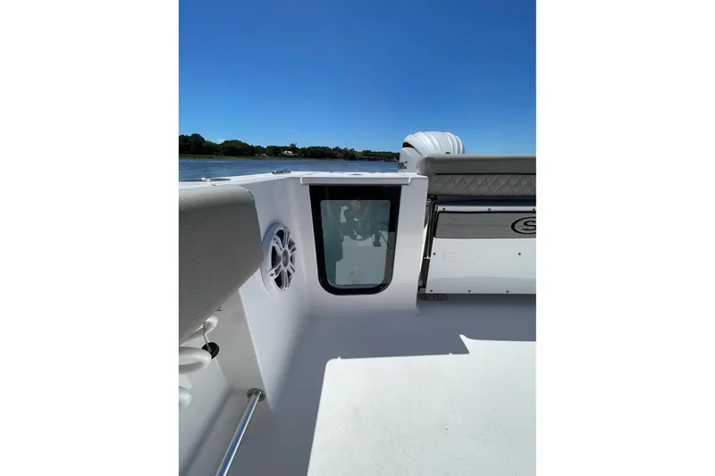 Slide: The Image of 2024 Sportsman Open 232 Center Console boat interior with seating and speaker, under clear blue sky. - 32