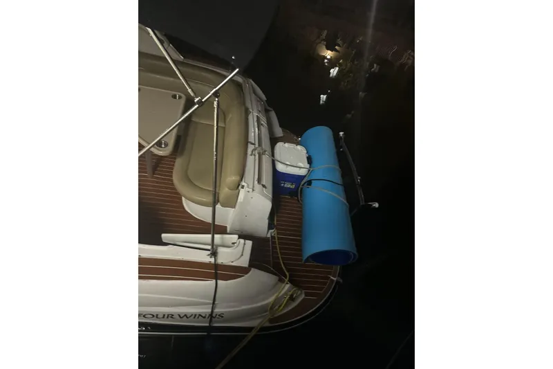 Slide: The Image of 2007 Four Winns V338 boat deck with seating, cooler, and blue mat at night. - 5