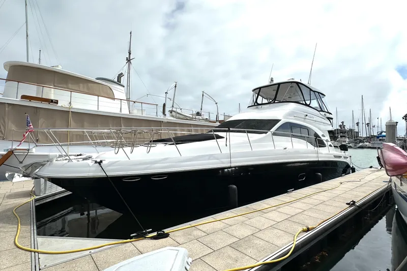 Slide: The Image of 2007 Sea Ray 580 Sedan Bridge yacht docked at marina under cloudy sky. - 2