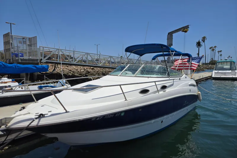 Slide: The Image of 2004 Chaparral Signature 240 boat docked with American flag, blue canopy, and clear sky. - 0