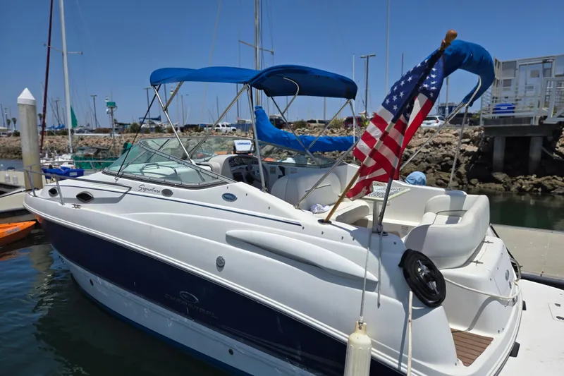 Slide: The Image of 2004 Chaparral Signature 240 boat docked, featuring blue canopy and American flag. - 1