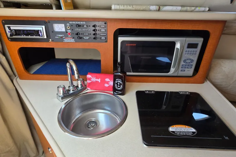Slide: The Image of 2004 Chaparral Signature 240 boat kitchenette with sink, microwave, and control panel. - 13