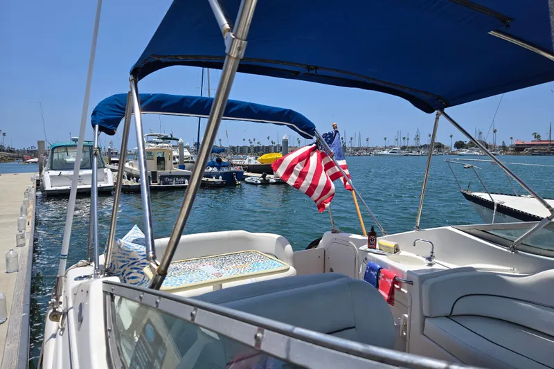 Slide: The Image of 2004 Chaparral Signature 240 boat docked, featuring American flag and blue canopy. - 4