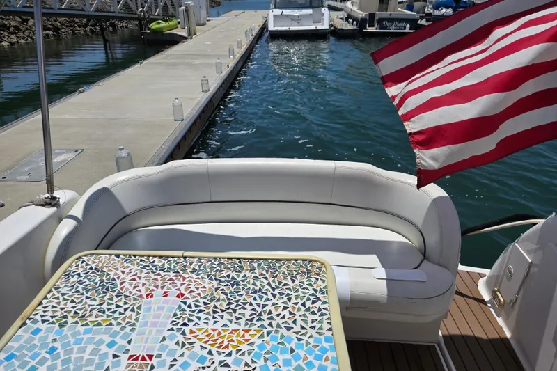 Slide: The Image of 2004 Chaparral Signature 240 boat with mosaic table, docked near water, American flag waving. - 6
