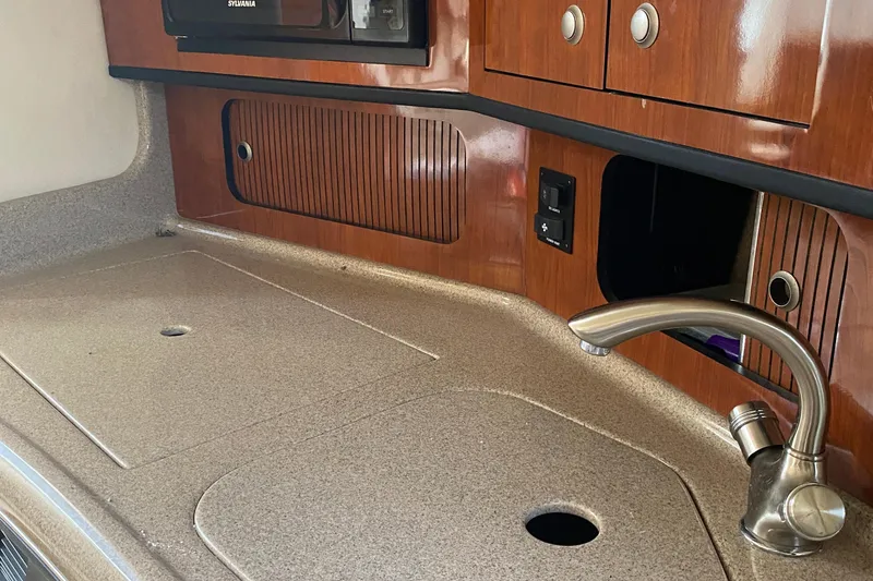 Slide: The Image of 2007 Sea Ray 300 Sundancer kitchen area with sink and wooden cabinetry. - 23