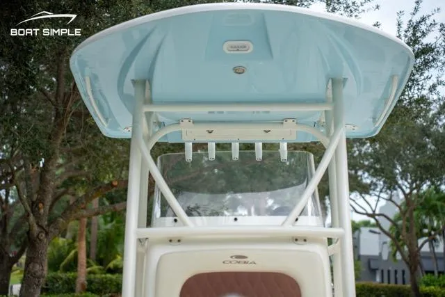 Slide: The Image of 2023 Cobia 240 Center Console boat with T-top, viewed from below, surrounded by trees. - 18