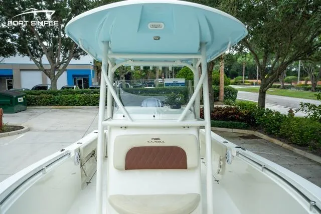 Slide: The Image of 2023 Cobia 240 Center Console boat, white interior, parked outdoors, with blue canopy. - 13