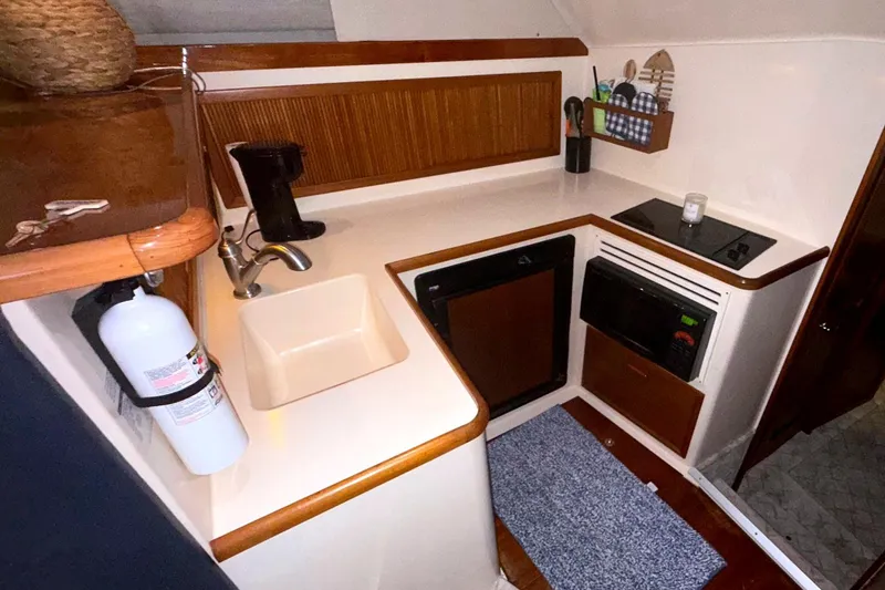 Slide: The Image of 1996 Riviera 39 Open Flybridge yacht kitchen with sink, stove, and microwave. - 20