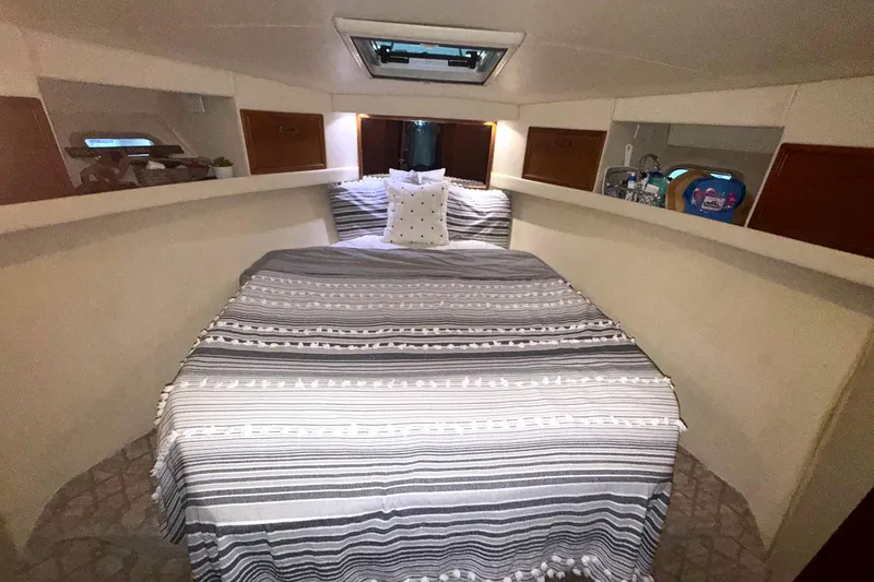Slide: The Image of 1996 Riviera 39 Open Flybridge cabin with striped bedding and cozy interior. - 22