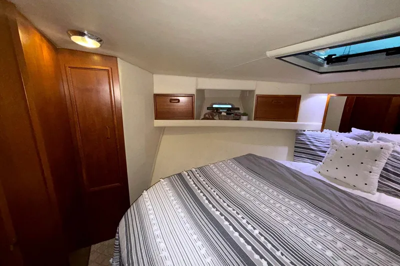 Slide: The Image of Cozy bedroom in 1996 Riviera 39 Open Flybridge yacht with striped bedding and wooden cabinets. - 23