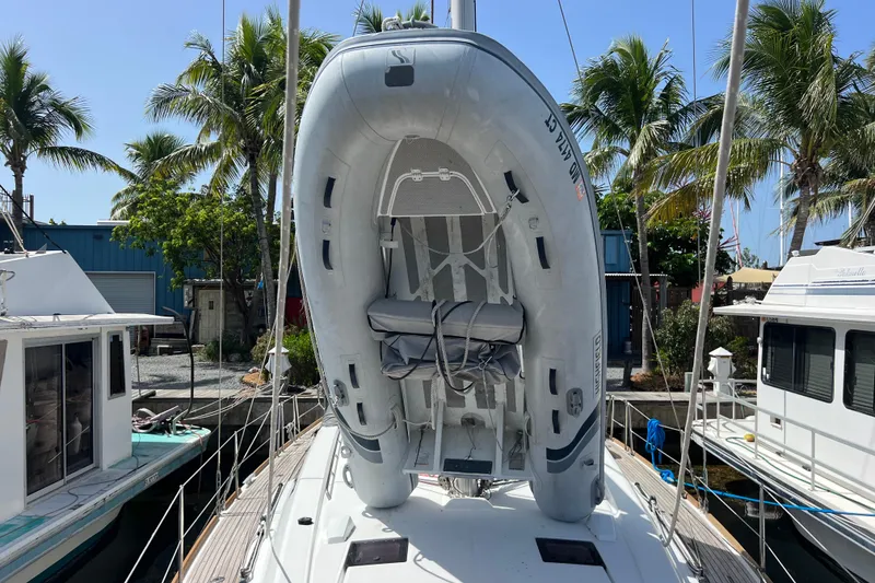 Slide: The Image of 2013 Beneteau Oceanis 45 sailboat with dinghy on deck, docked near palm trees. - 32