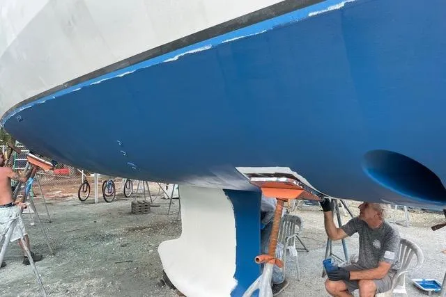 Slide: The Image of 2013 Beneteau Oceanis 45 yacht undergoing maintenance, with workers painting the hull blue. - 42