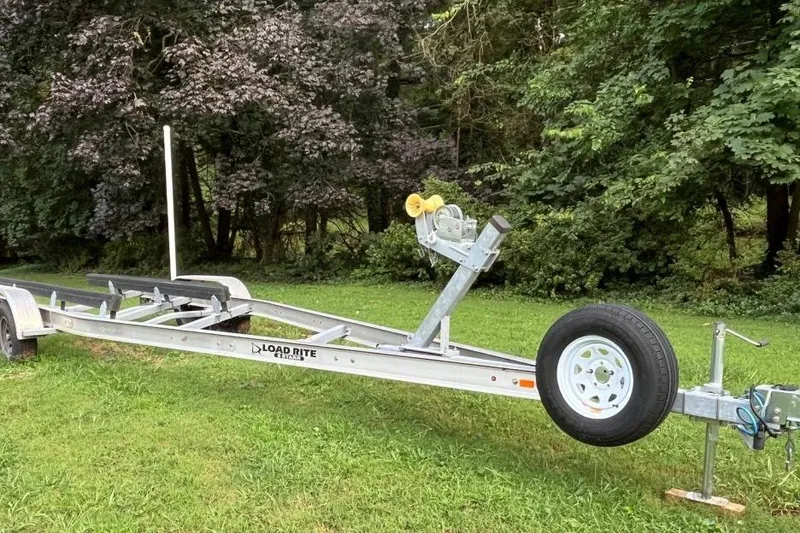 Slide: The Image of Boat trailer on grass, Load Rite brand, surrounded by lush trees. - 25