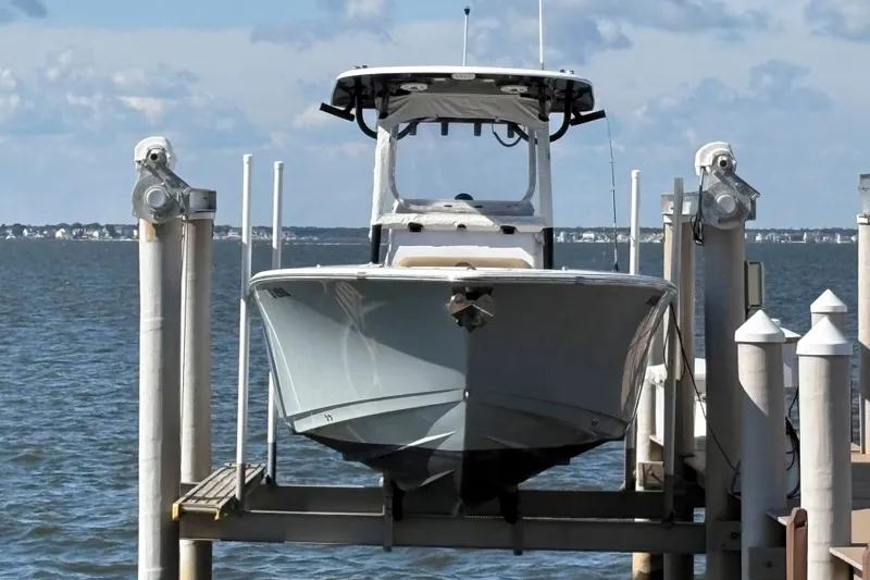 Slide: The Image of 2018 Sportsman Open 252 Center Console boat docked on a lift by the water. - 2