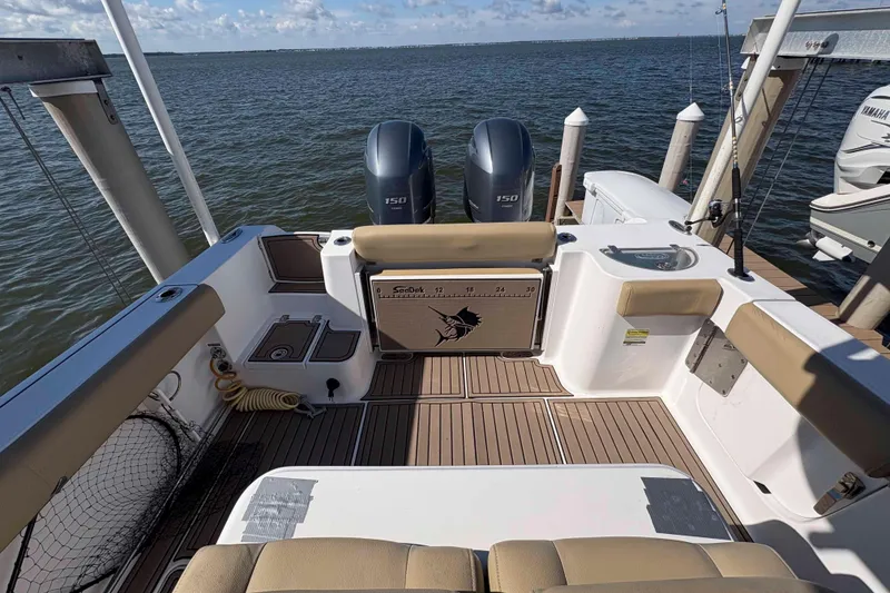 Slide: The Image of 2018 Sportsman Open 252 Center Console boat interior with twin engines, docked by the water. - 7