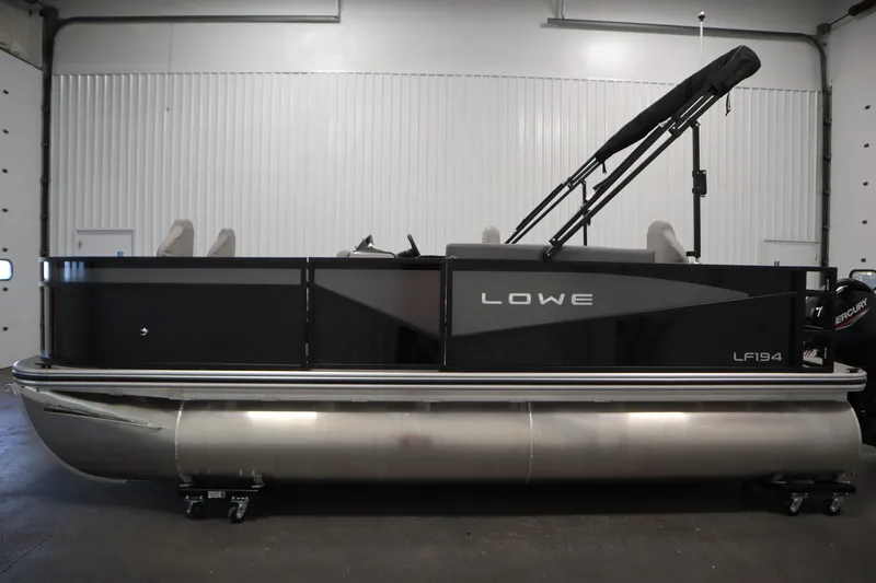 Slide: The Image of 2026 Lowe LF 194 pontoon boat in a showroom, featuring sleek black design and modern seating. - 7