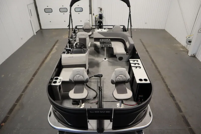 Slide: The Image of 2026 Lowe LF 194 pontoon boat interior with seating and steering wheel in a garage. - 8