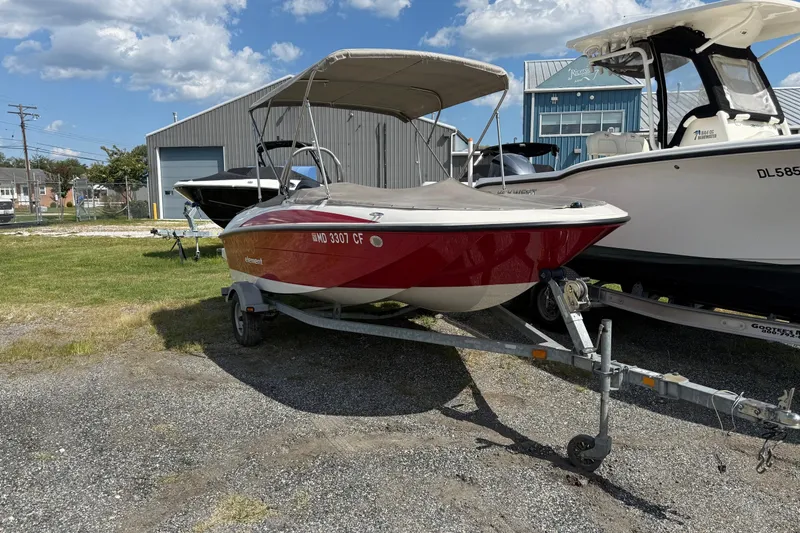 Slide: The Image of 2013 Bayliner Element boat on trailer, parked outdoors near other boats. - 4