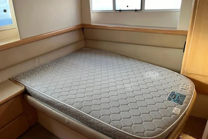 Slide: The Image of 1998 Carver 355 Aft Cabin interior with a neatly made bed and window view. - 22
