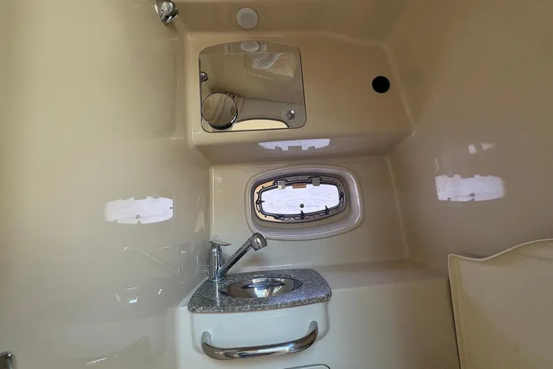 Slide: The Image of 2011 Chaparral 330 Signature boat bathroom with sink, mirror, and porthole window. - 24