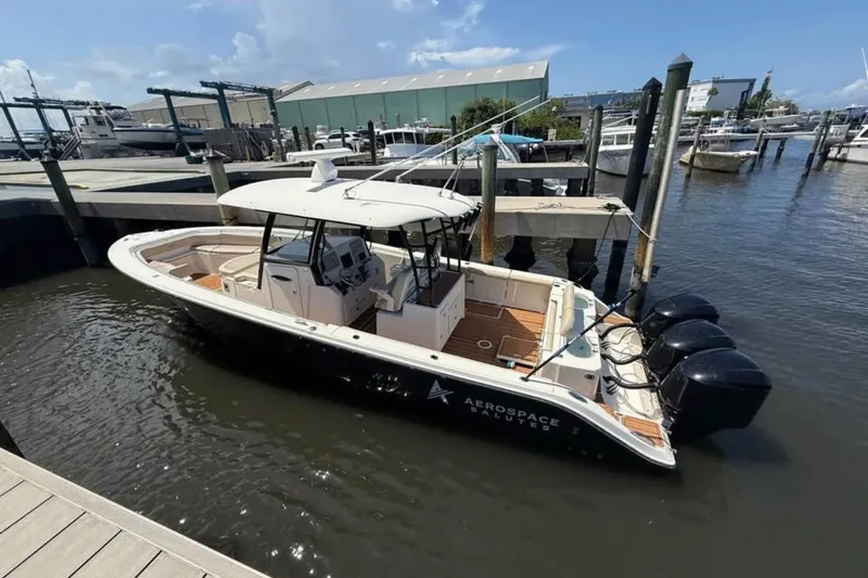 Slide: The Image of 2015 Cobia 344 Center Console boat docked at marina with triple outboard engines. - 2