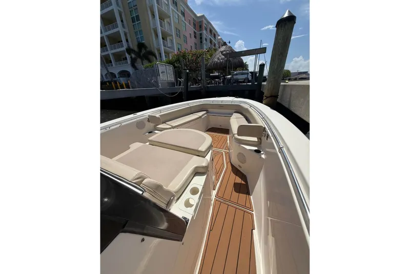 Slide: The Image of 2015 Cobia 344 Center Console boat docked, featuring spacious seating and teak flooring. - 7