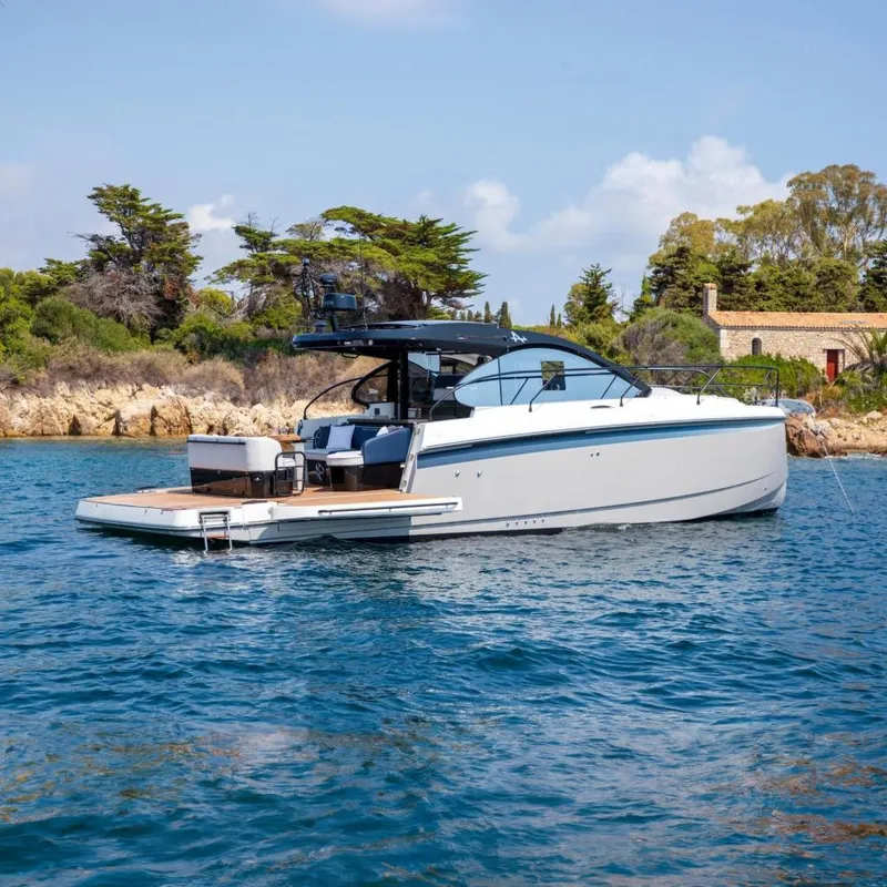 Slide: The Image of 2026 Beneteau Gran Turismo 40 yacht on serene water near a rocky shoreline. - 11