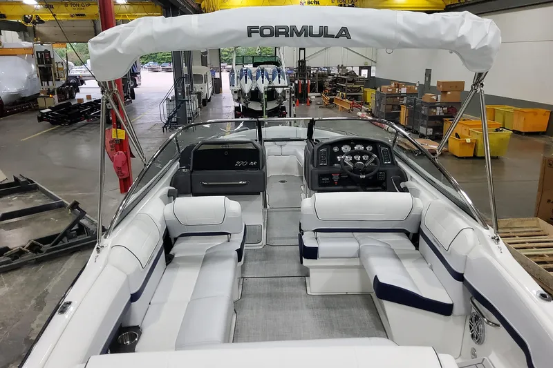 Slide: The Image of 2026 Formula 270 Bowrider boat interior with white seating and modern dashboard in a warehouse. - 9