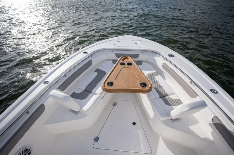 Slide: The Image of Bow seating area of 2026 Caymas 291 boat with wooden table on water. - 13