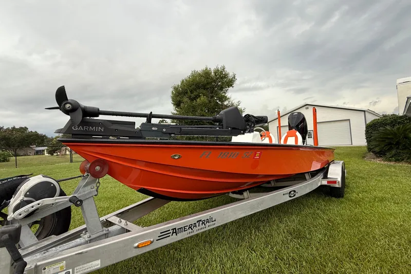 Slide: The Image of Orange Big O Elite 20 boat on trailer, grassy yard, overcast sky. - 3