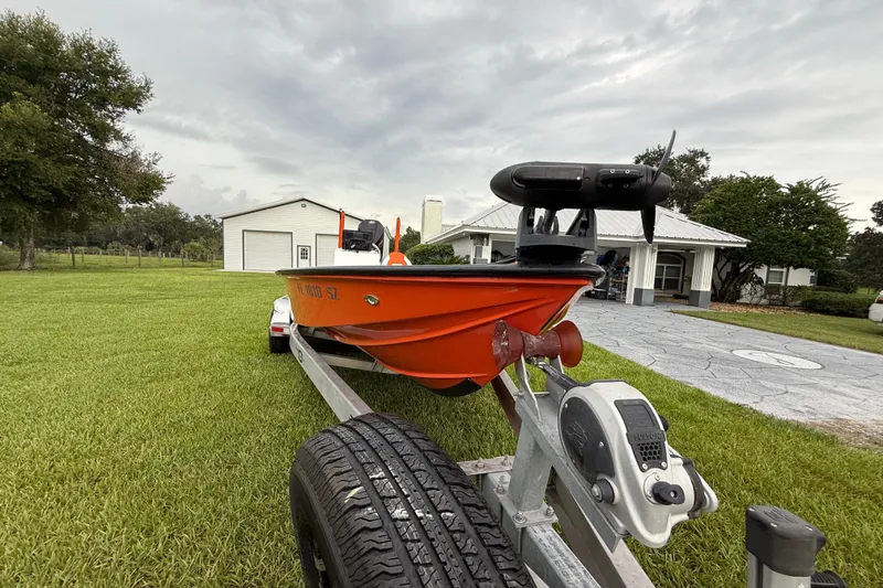 Slide: The Image of Orange Big O Elite 20 boat on trailer, parked on grass near a white building. - 4
