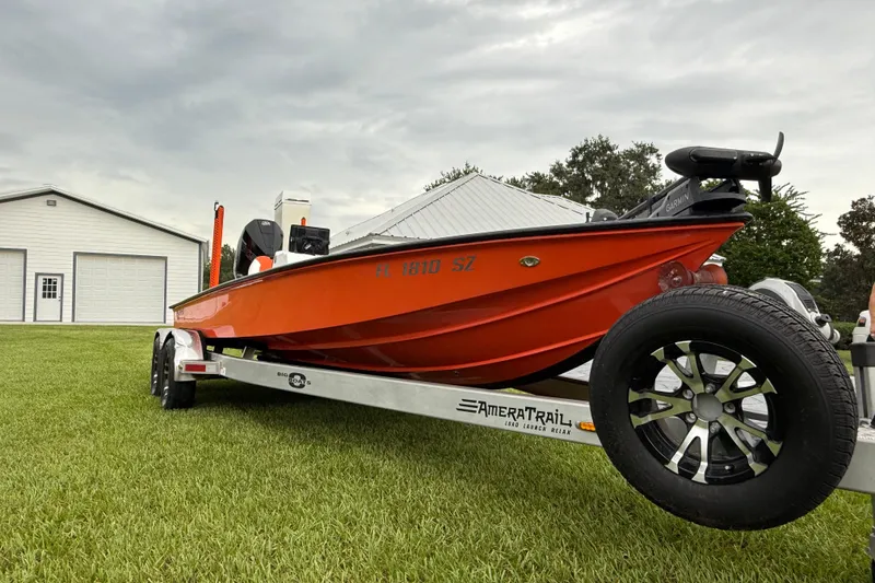 Slide: The Image of 2021 Big O Elite 20 boat on trailer, parked on grass near a white building. - 5