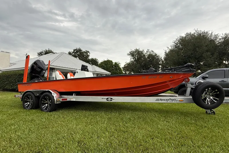 Slide: The Image of Red Big O Elite 20 boat on trailer, parked on grass, overcast sky. - 6