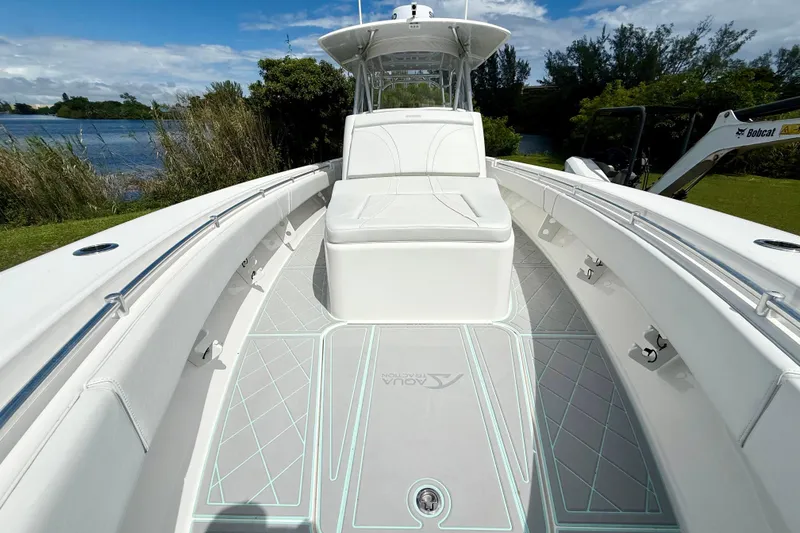 Slide: The Image of 2023 Contender 39 Fisharound boat with sleek white deck and seating, near a scenic waterway. - 12
