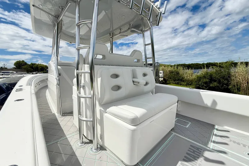 Slide: The Image of 2023 Contender 39 Fisharound boat with white seating and stainless steel ladder under a blue sky. - 17