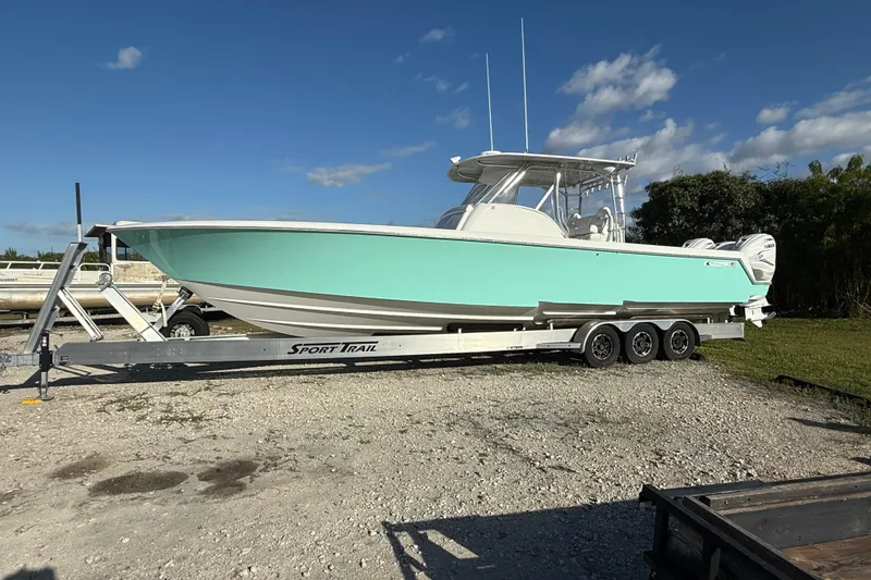 Slide: The Image of 2023 Contender 39 Fisharound boat on trailer, light blue hull, parked outdoors. - 21