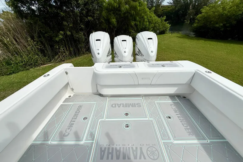 Slide: The Image of 2023 Contender 39 Fisharound boat deck with triple engines, lush greenery background. - 6