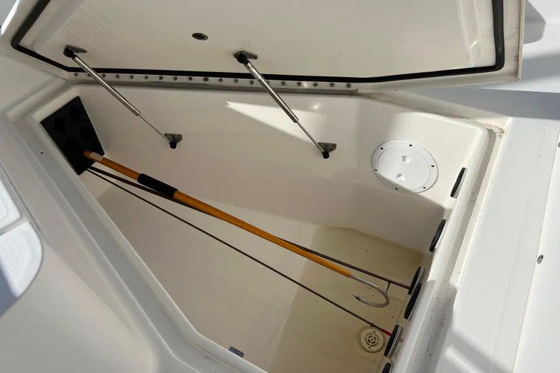 Slide: The Image of Open storage compartment in 2012 Regulator 24 Forward Seating boat, featuring hydraulic struts and fishing gaff. - 30