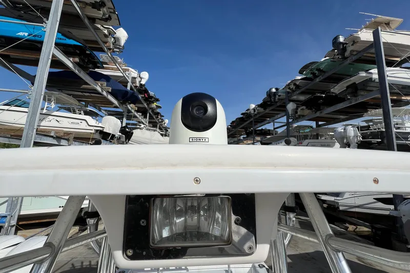 Slide: The Image of 2012 Regulator 24 Forward Seating boat in storage, surrounded by stacked boats under clear blue sky. - 36