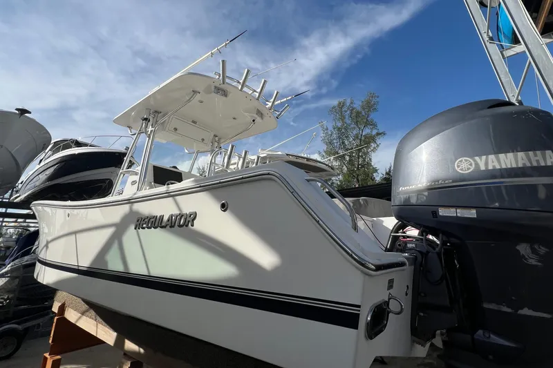 Slide: The Image of 2012 Regulator 24 Forward Seating boat with Yamaha engine, docked under clear blue sky. - 4